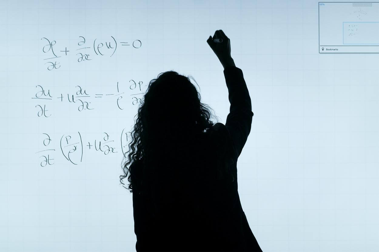 Girl writing formula in white board.