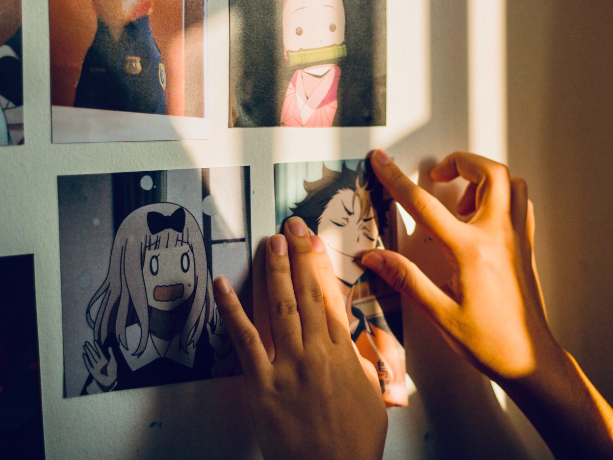 A person is attaching a picture of animated character on the wall