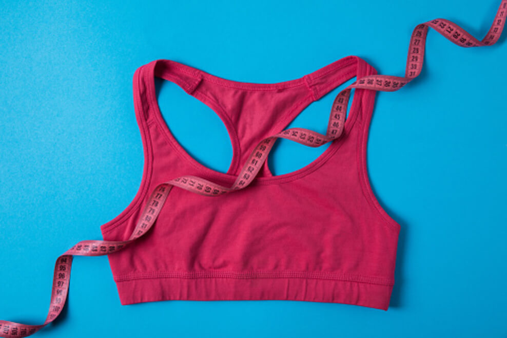 Elevated depiction of a pink bra along with measuring tape