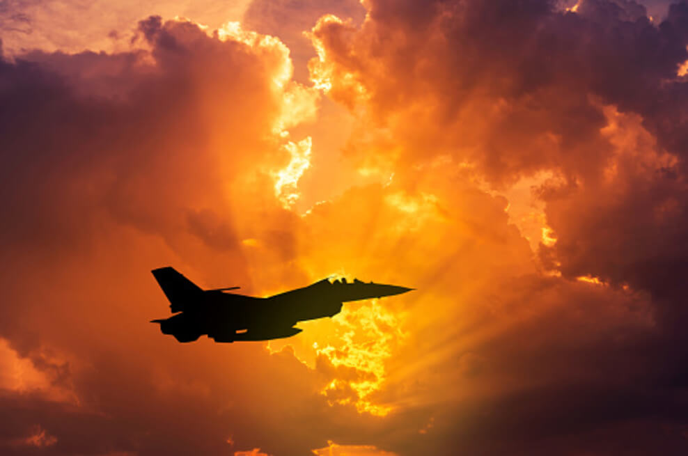 The military F-16 flying with sunset captured in the background