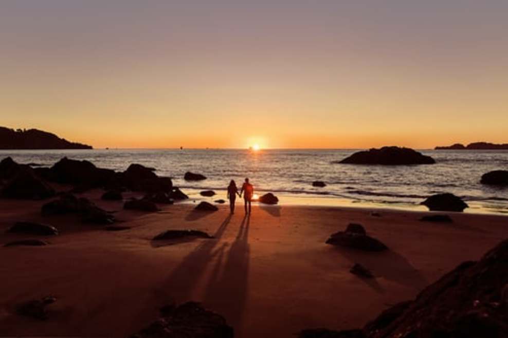 An image of a couple at a beach with sunset being captured too