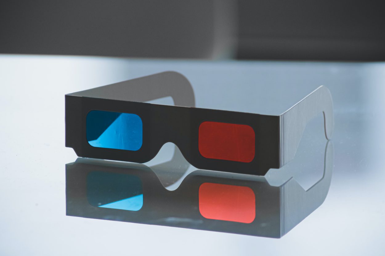 A pair of black 3D glasses with its reflection