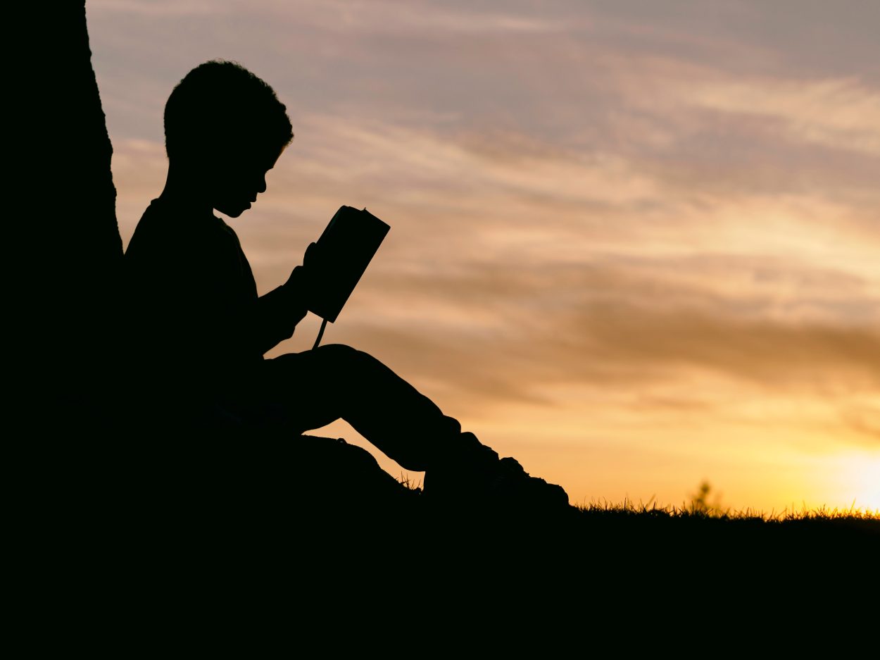 A silhouette of a kid reading