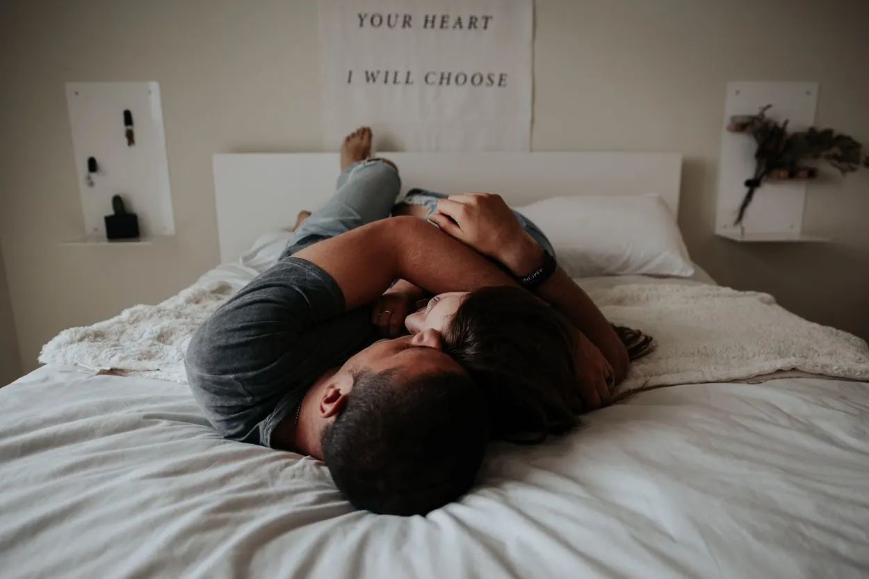 Two people cuddling in bed