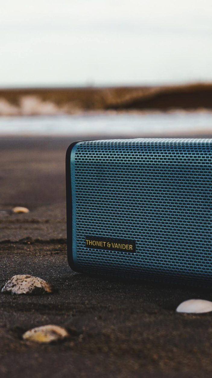 A portable speaker placed horizontally onto a rocky surface
