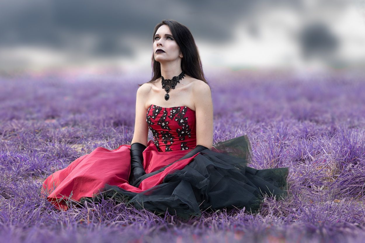 A person in a black and red gown looking up at the sky