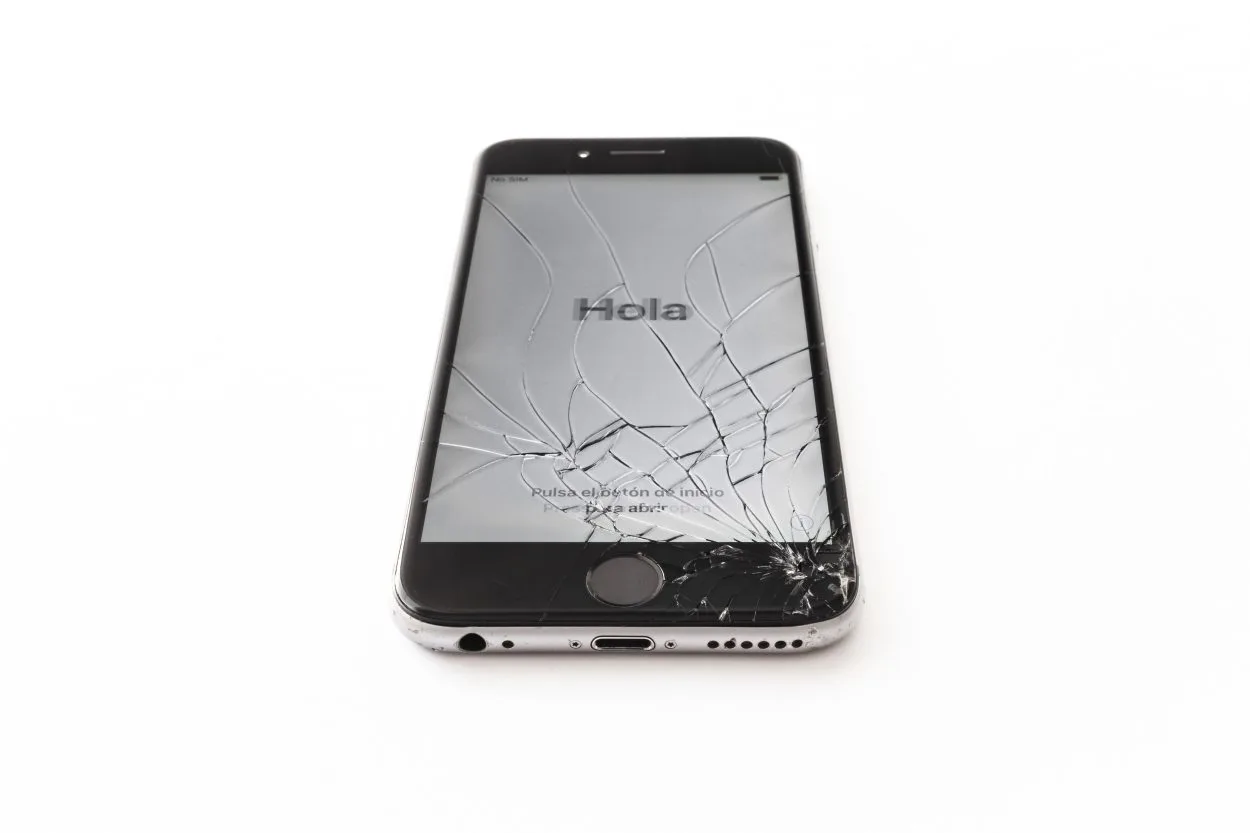 A phone with shattered screen saying 'Hola'