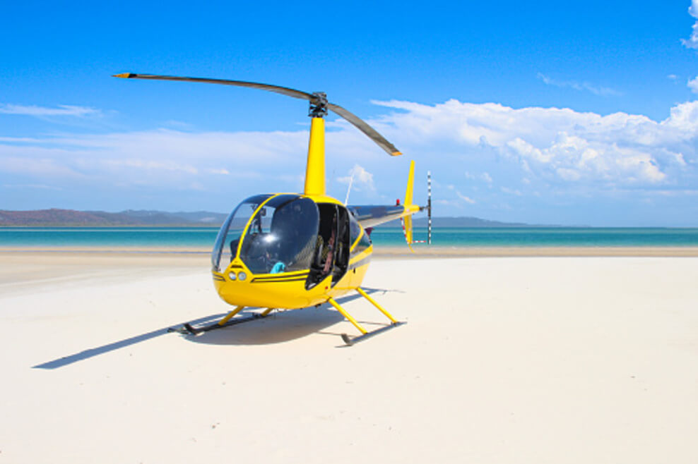 A picture of a yellow chopper near a beach.