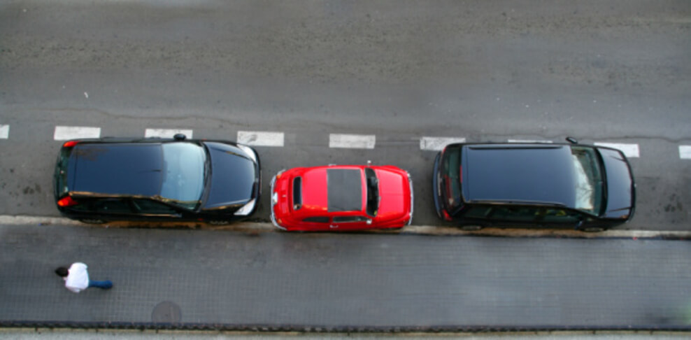 An image showing a few cars parked in a queue with less space occupied.