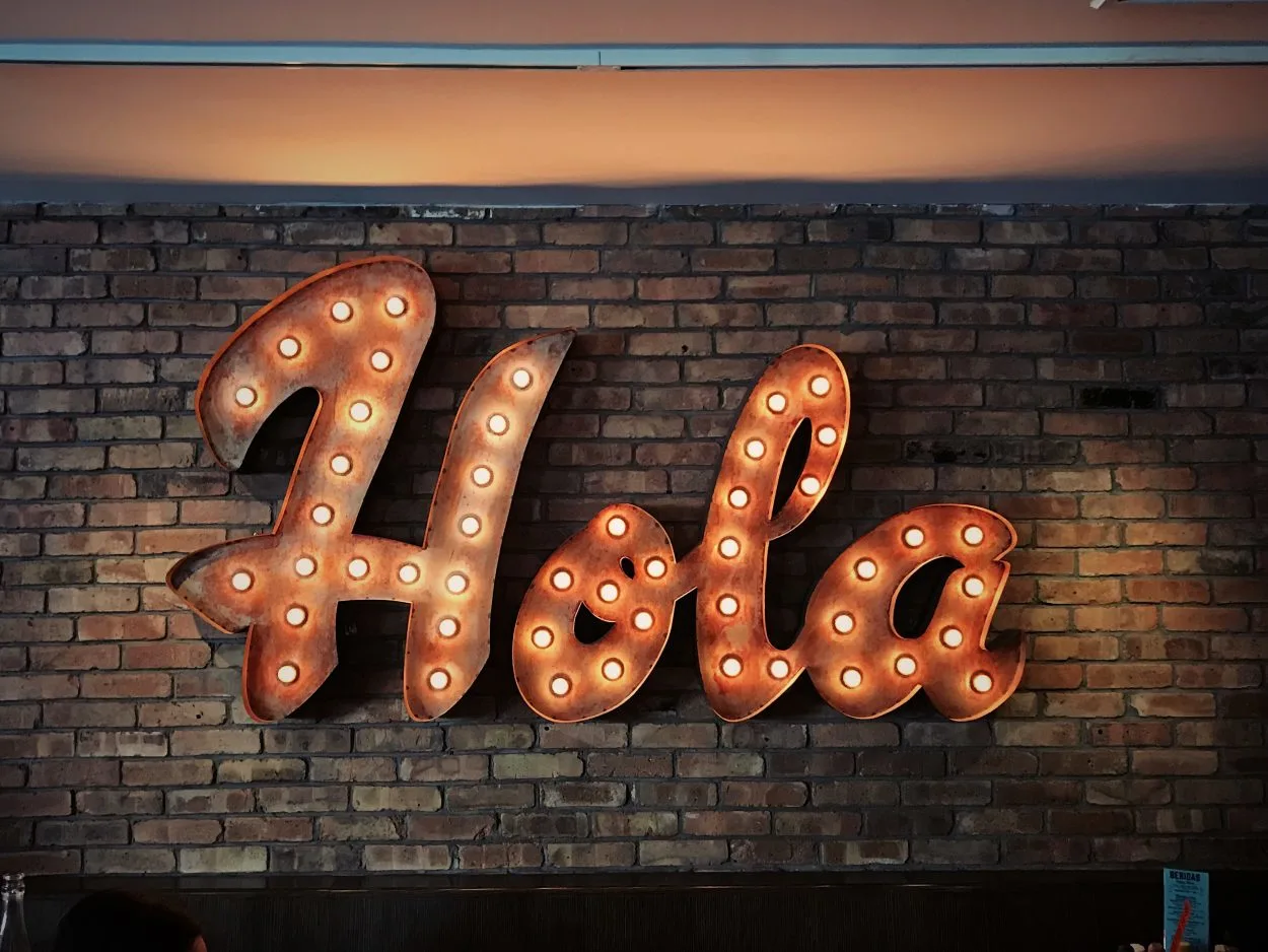 A brick wall that has is decorated with the Spanish word 'Hola'