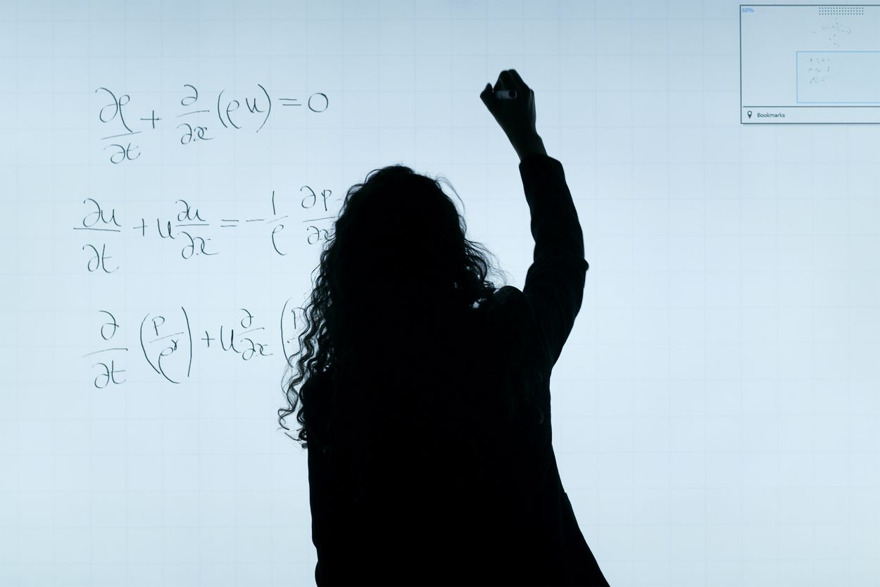 An image of girl writing on a white board.