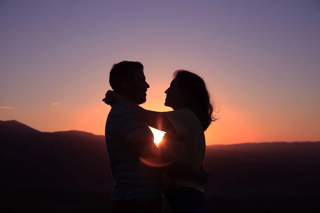 Two people in front of a sunset