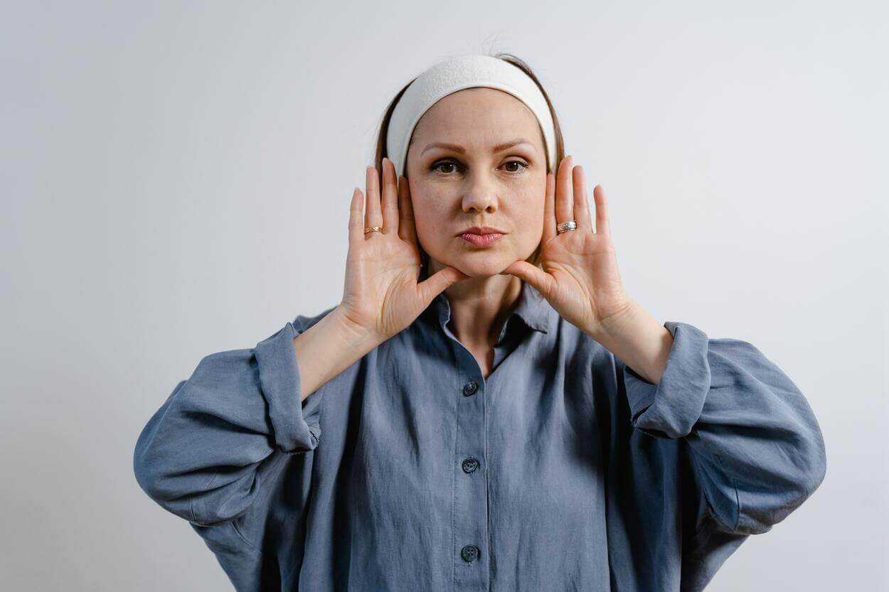 Woman touching her cheeks with both hands.