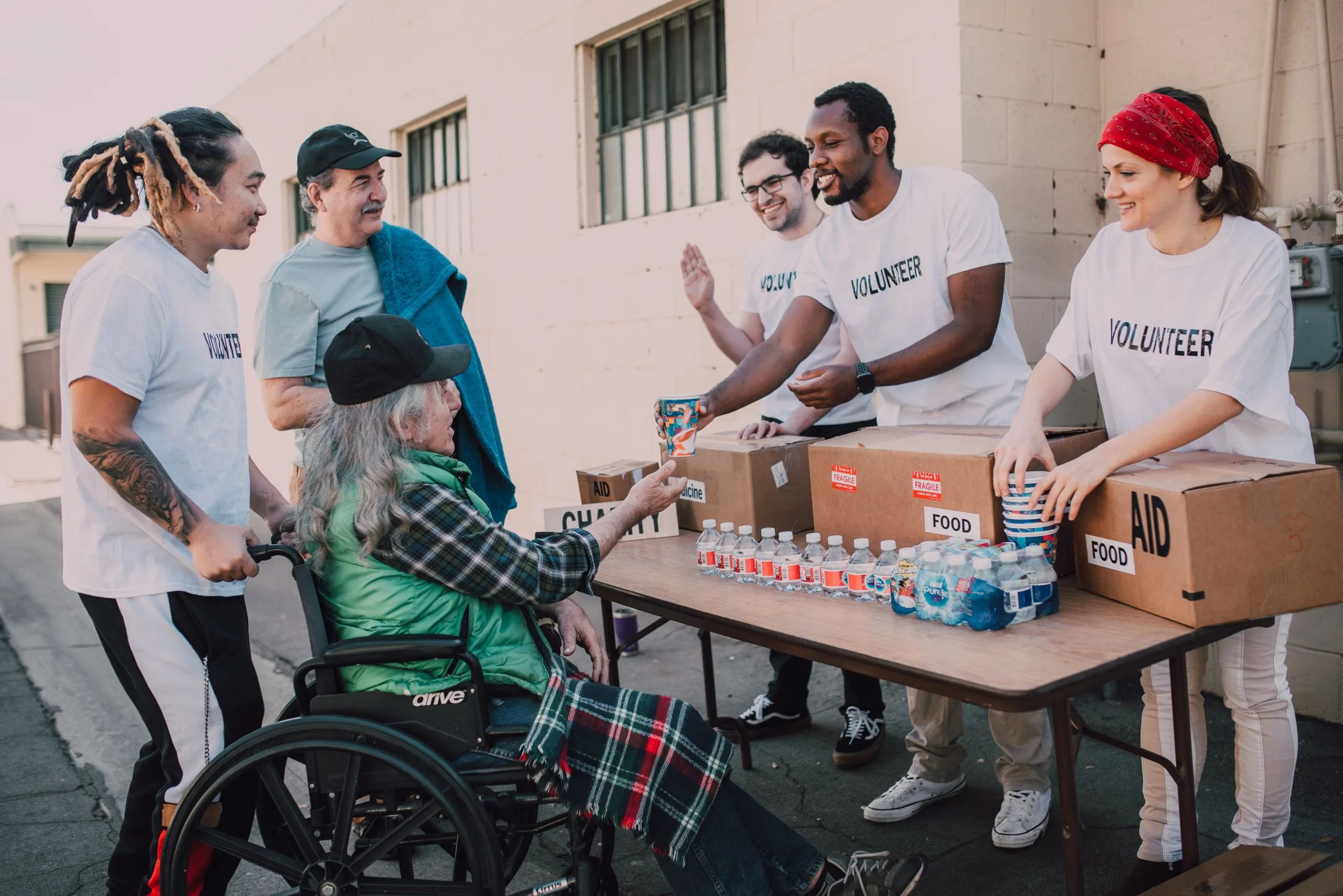 Volunteers giving a cup to an elderly person