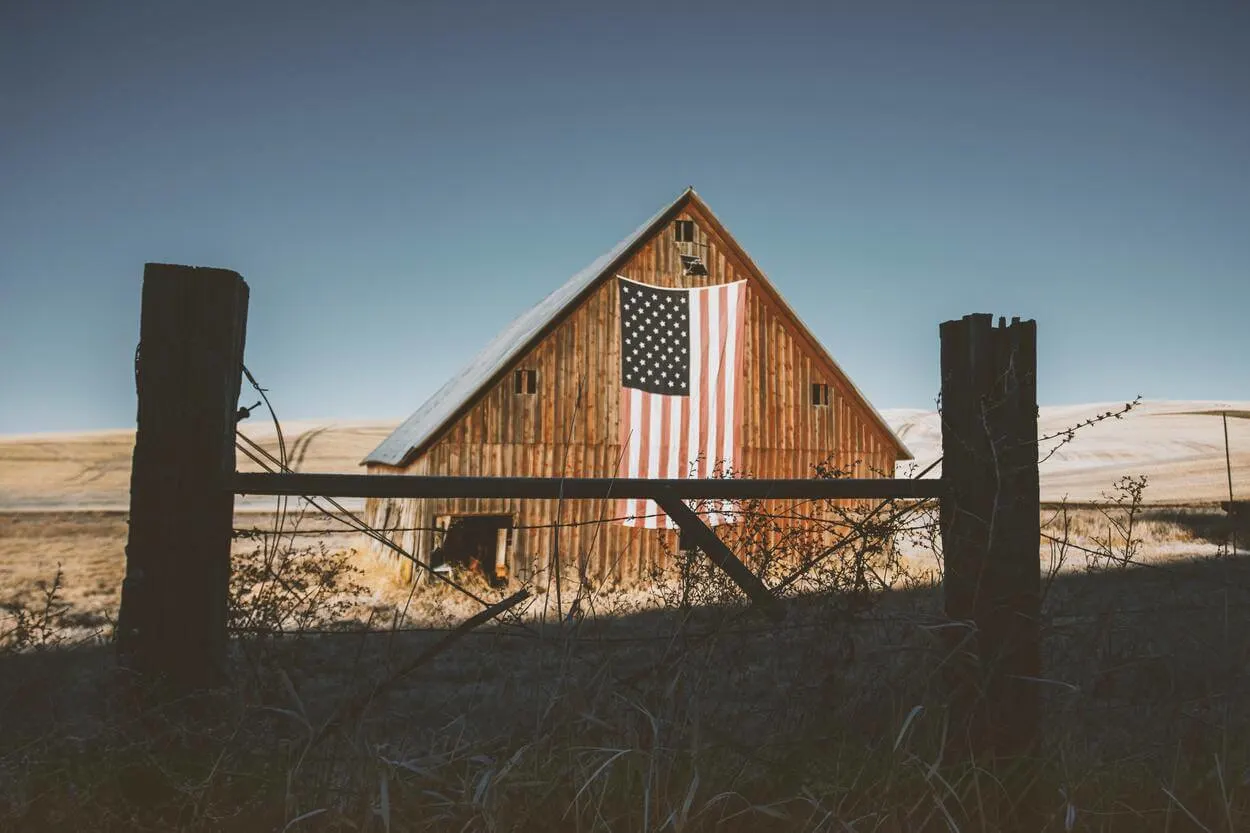 Barn in the countryside of America with the country's flag.
