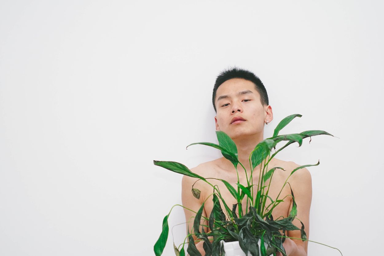 A person naked behind a plant