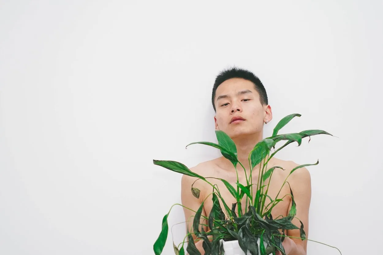 A person naked behind a plant
