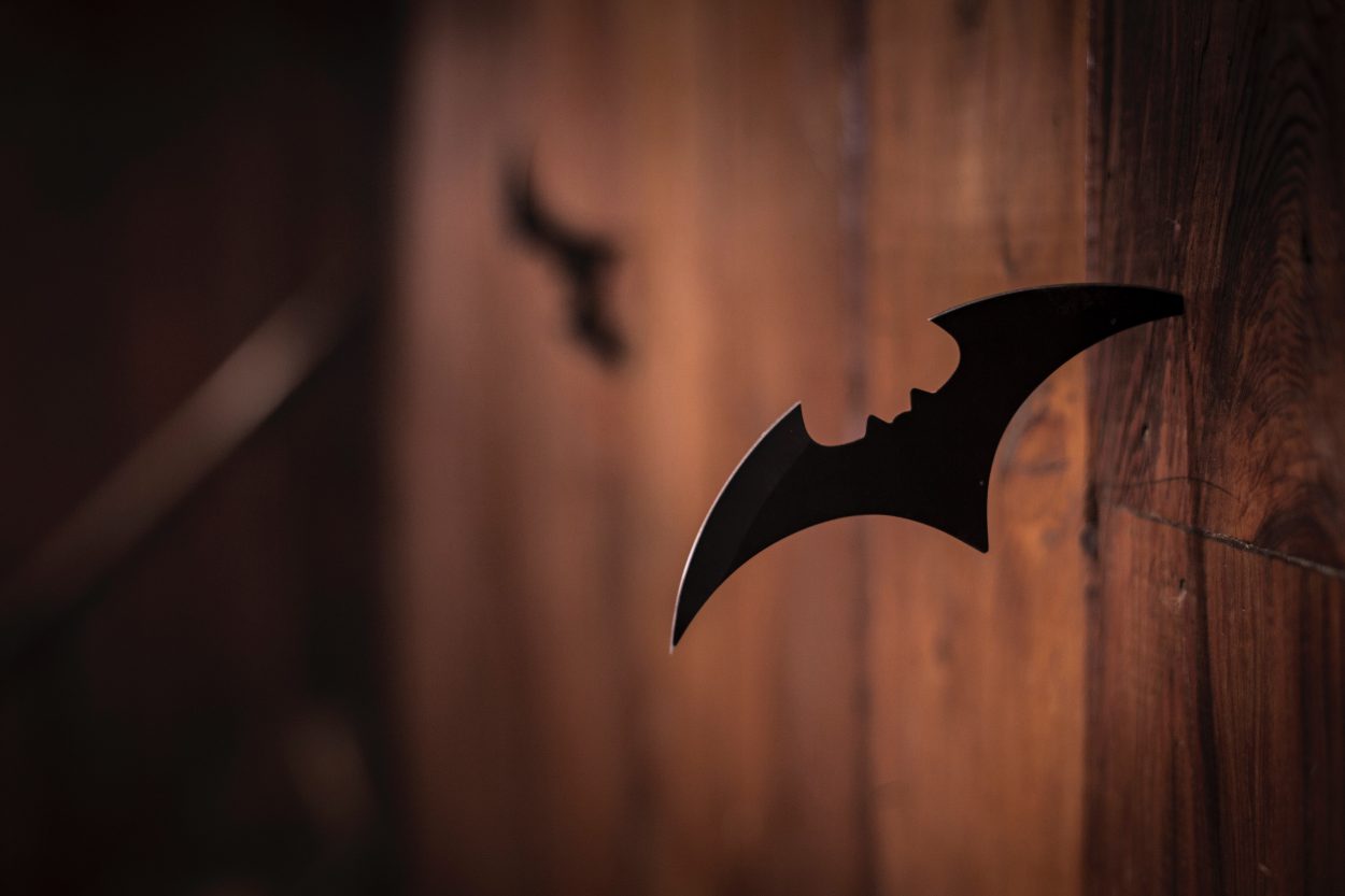 A throwing knife in the shape of Batman's symbol stuck to the wall.