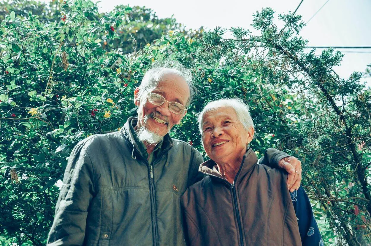 An old couple posing for a picture with smiles on their face. 