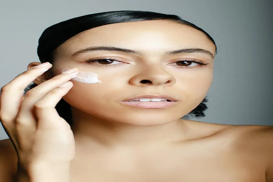 A woman applying facial cream on her face.