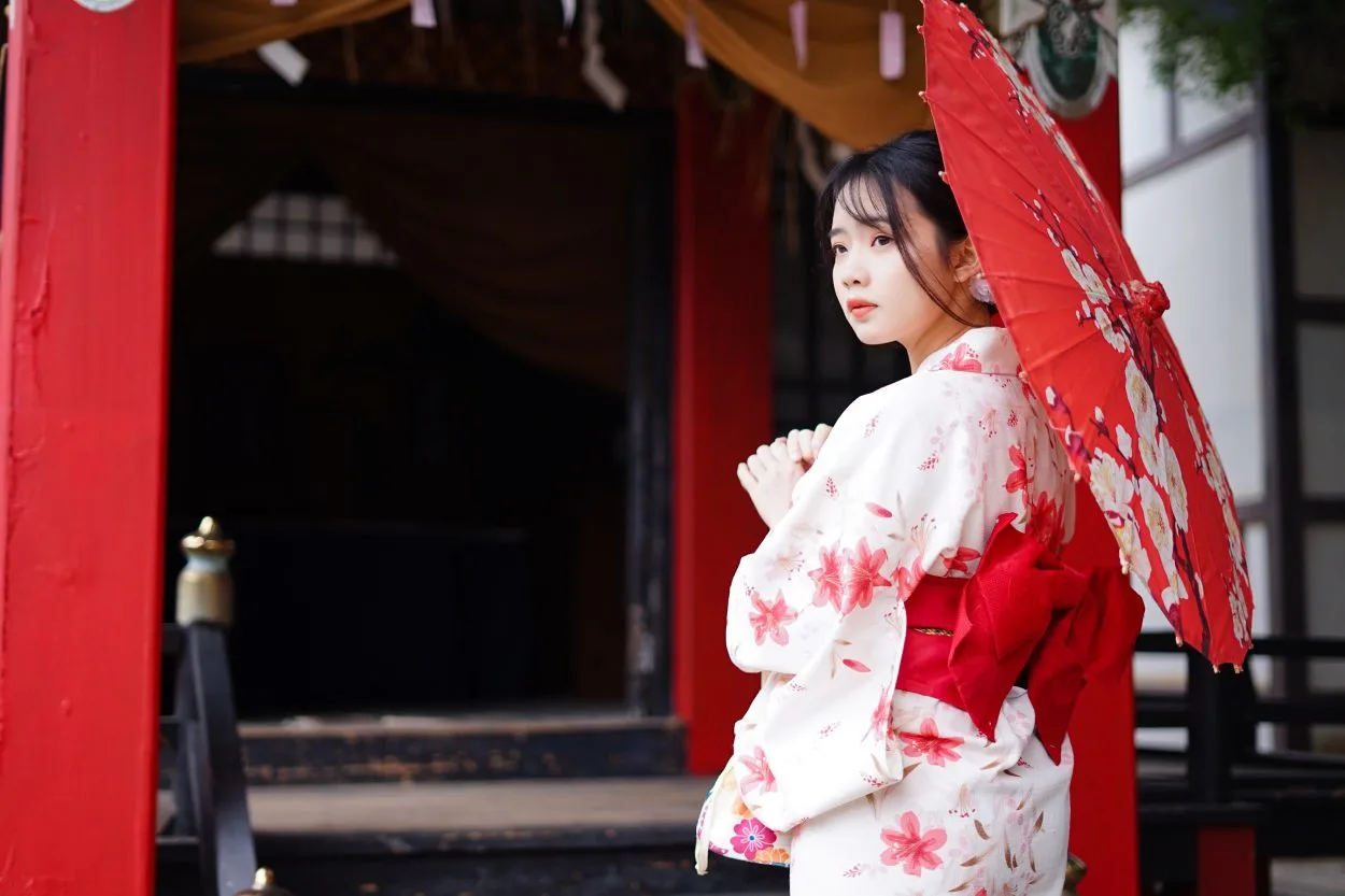 A woman dressed in Japanese traditional clothing holding an traditional red colored paper umberalla 