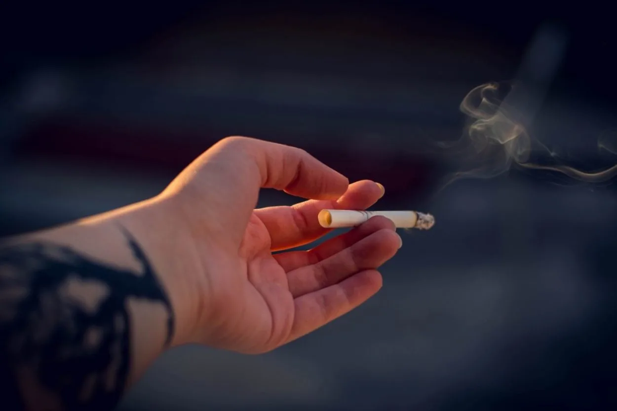 Picture shows someone holding a lighted cigarette.