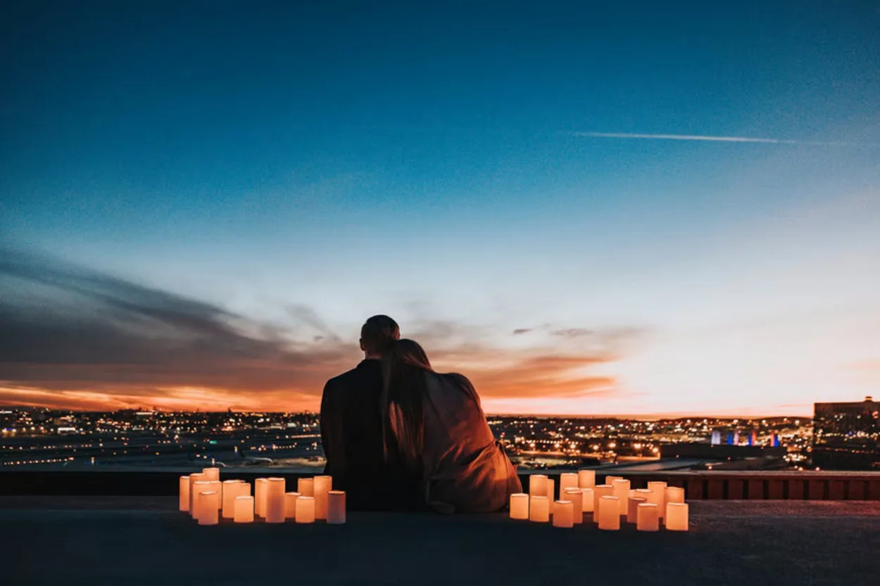 a couple sitting over a city with a bunch of lanterns