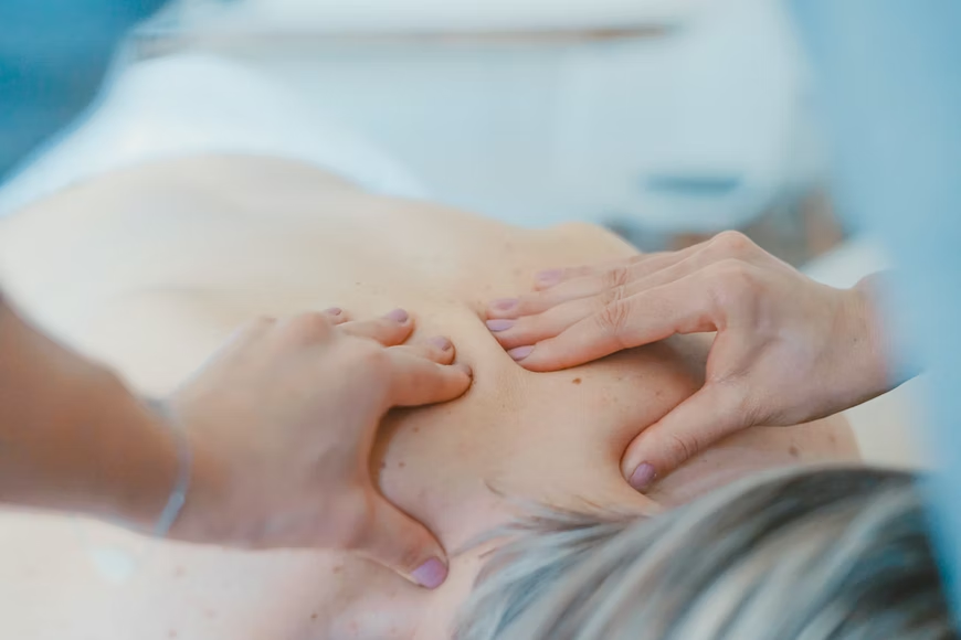 person massaging the back of a woman suffering from backpain