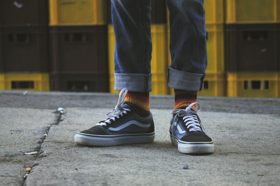 A person wearing black and blue Vans Old Skool.