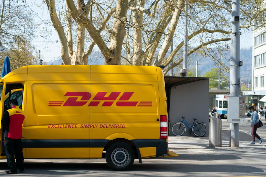 A man standing in front of a DHL delivery van.