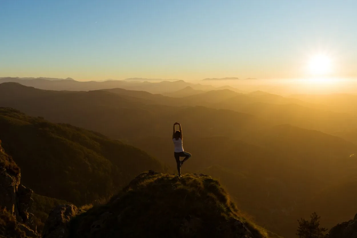 A women meditating on top of a mountain in the middle of nowhere.