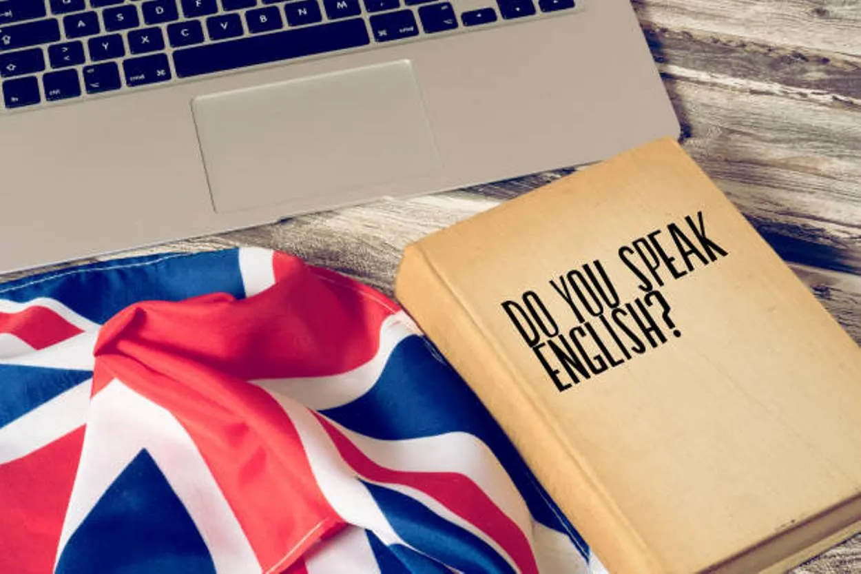 A computer, the flag of Great Britain, and a book titled Speak English