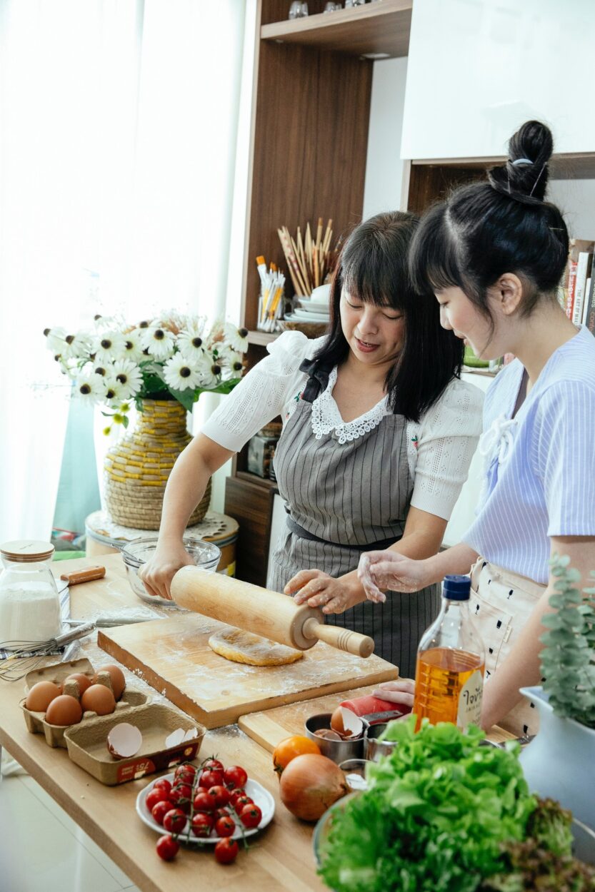 Asian women making dough in kitchen
