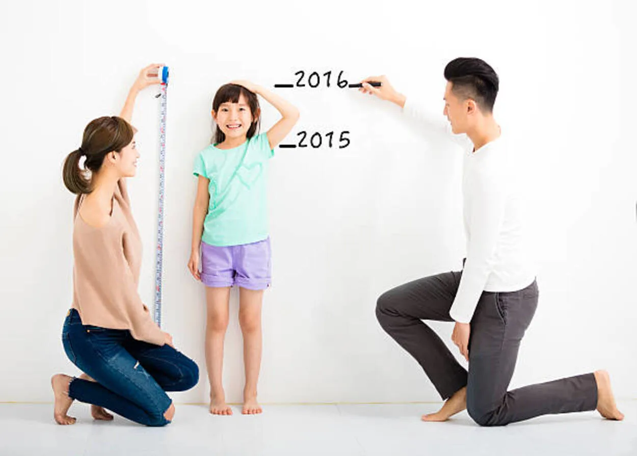 Image of parents measuring height of their daughter. 