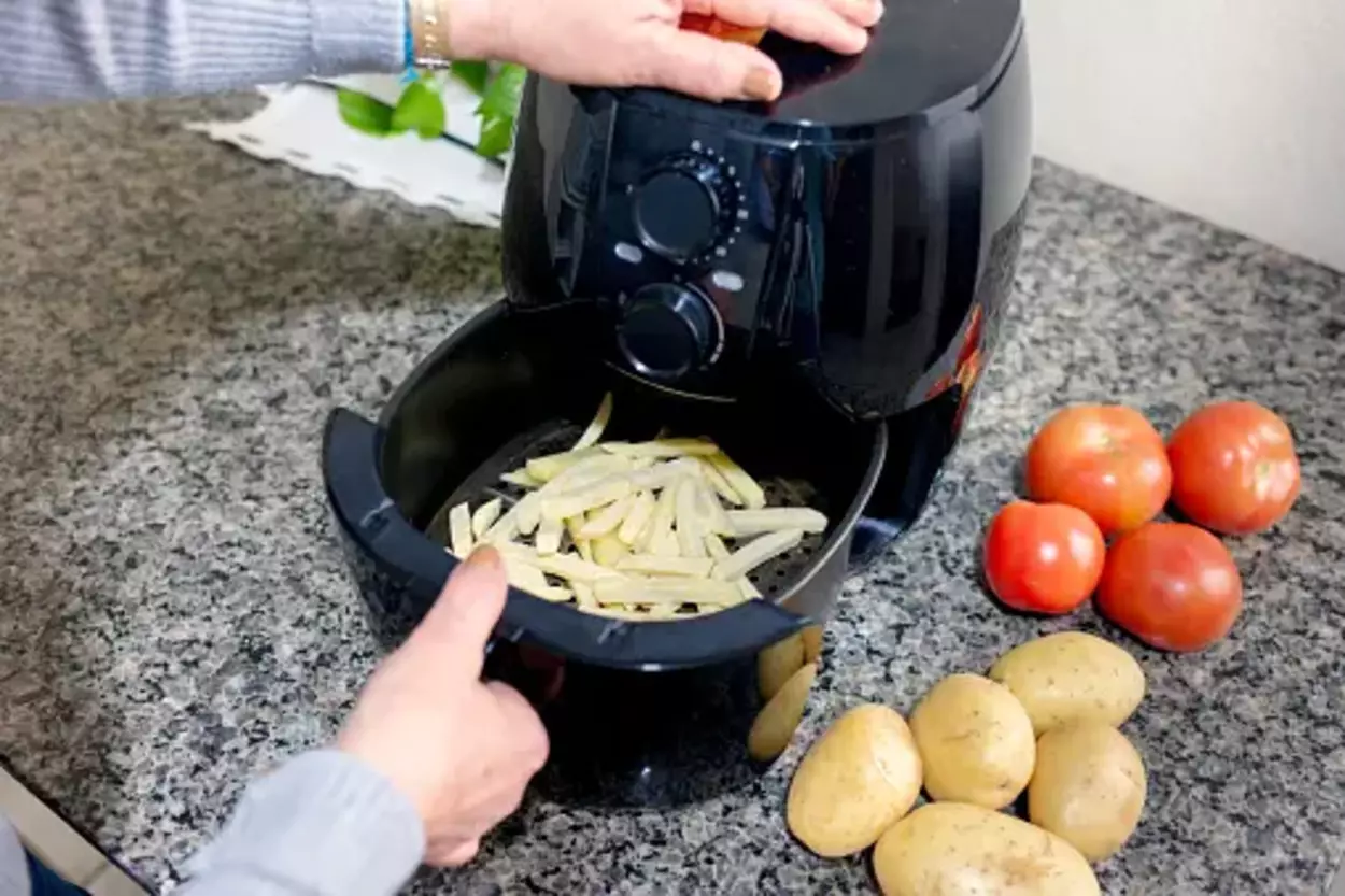 A air fryer basket with vegetables besides them